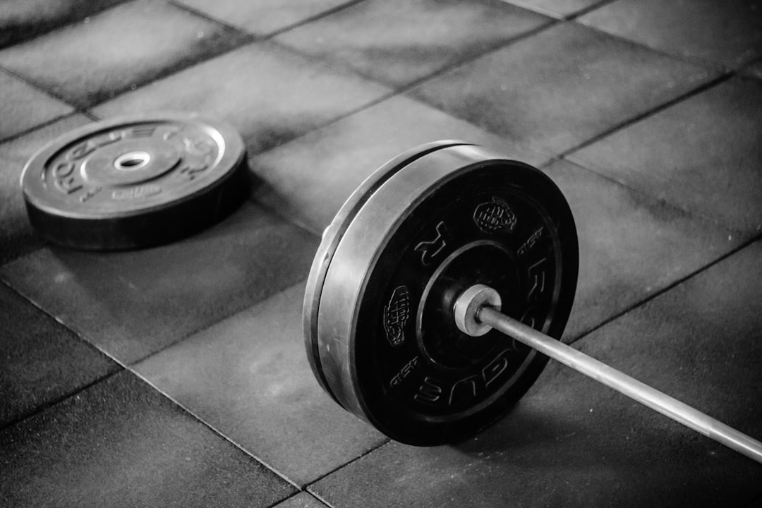 Black barbell on tile flooring at PS Fitness Gym